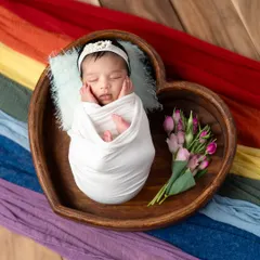 Nestled in a heart-shaped wooden bowl, this sleeping baby looks so peaceful. I added a small bouquet of tulips to bring a touch of color and softness to this newborn portrait.