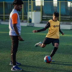 A coach provides one-on-one guidance to a youth player during a drill. This personalized feedback is key to helping each athlete understand and improve their ball control and shooting form.