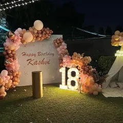 Here’s a chic 18th birthday I decorated on a terrace. I used marquee light-up numbers and a custom backdrop with the birthday person's name, framed by a stylish organic balloon arch in peach and rose gold tones for a sophisticated evening celebration.