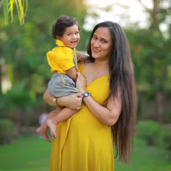 A mother and her son share a beautiful smile in this sun-kissed outdoor portrait. The warm light and natural green background create a perfect setting for family photos.
