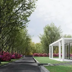 The approach to this weekend retreat is through a driveway lined with mature trees and flowering bushes. The minimalist, glass-walled pavilion appears at the end of the path, creating a sense of arrival at a private and secluded natural oasis.