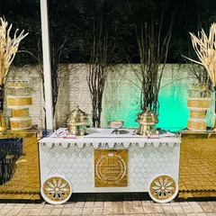 A custom-designed food cart in white and gold, part of a themed catering setup. This adds a unique and stylish element to the buffet, moving beyond standard table arrangements.