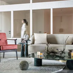 This living area is a masterclass in color balance. Muted red chairs add warmth, grounded by a rich green marble coffee table. A pale green rug provides a soft foundation, creating a look that nods to Art Deco glamour in a contemporary way.