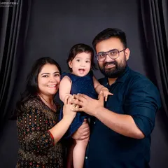 A joyful and energetic family portrait. The parents are holding their laughing daughter, and their happiness is contagious in this lovely shot.
