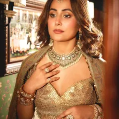 The stunning Hina Khan looking regal in a full bridal ensemble. She wears an emerald and polki choker, stacked kundan bangles, statement rings, and a maang tikka, creating a look of unparalleled grandeur.