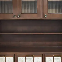 A crockery unit combining fluted glass, dark-stained wood, and custom floral tiles. This piece balances display and storage, with the handmade tiles adding a personal, artistic touch to the functional drawers.