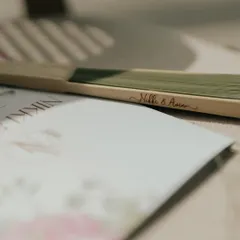 A close-up of a personalized wedding program and a hand fan, engraved with the couple's names, Nikki & Avin. These small, bespoke items make guests feel truly welcomed.