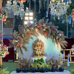 A sacred Ganesha installation at the entrance of an outdoor wedding, beautifully decorated with pampas grass, florals, and chandeliers to welcome guests with blessings.
