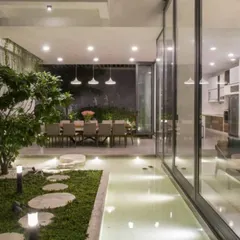 The same semi-indoor garden at night. With carefully placed uplighting and ambient light from the house, the space transforms into a magical, serene landscape that can be enjoyed 24/7.