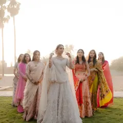 A beautiful portrait of the bride with her bridesmaids, all standing together in a field during golden hour.