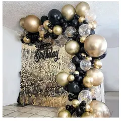 This glamorous birthday photo booth features a full gold shimmer sequin wall as a backdrop. It is framed by an elegant balloon arch made of black, gold, and transparent confetti balloons for a very classy party look.
