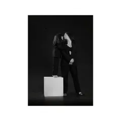 A daughter stands on a white block to give her mother a gentle kiss. This image is a beautiful blend of playful composition and classic, dramatic lighting, creating a timeless family portrait.