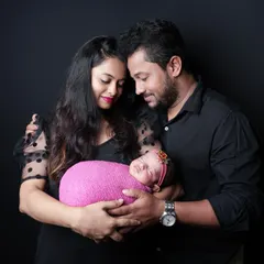 A loving portrait of a new family, with the baby girl wrapped in a bright pink swaddle that coordinates with her mother's dress. These shots capture the joy and tenderness of welcoming a new baby.