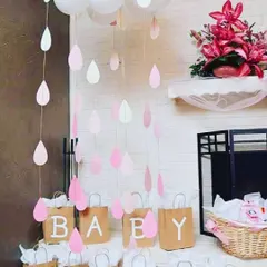 A close-up of my 'Simple n Shower' baby shower theme. This creative setup includes paper raindrops hanging from above and custom paper bags spelling out 'BABY', perfect for holding gifts or party favors.