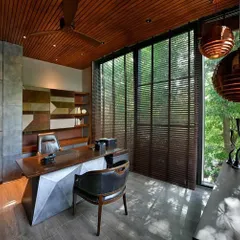 The study in the T House is a space for contemplation, cantilevered towards the garden. The room features a custom rosewood desk, copper pendant lights, and a leather-and-suede back unit, creating a powerful and tranquil workspace.