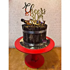 A "Cheers to 30" birthday cake designed as a wooden champagne bucket. The cake is topped with a miniature edible bottle and a custom topper.