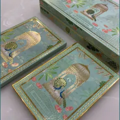 The complete wedding invitation box set, highlighting the consistent and regal peacock design on both the main box and the individual sweet boxes inside.