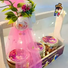 A close-up of the pink-themed wooden basket hamper, showing the fairy lights and custom-labeled jars.
