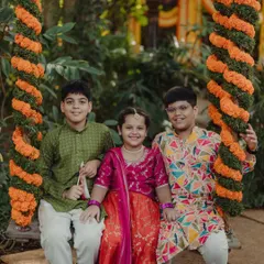 A lovely group portrait of the children on the floral swing. Their colorful traditional outfits and happy smiles make for a heartwarming and memorable photo.