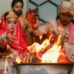 A powerful shot of the couple making offerings to the sacred fire during their pheras. The flames illuminate their faces, creating a dramatic and symbolic image that represents the vows they are taking together.
