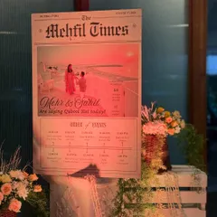 A creative and personalized welcome sign designed like a newspaper, "The Mehfil Times," announcing the couple's wedding and the order of events.