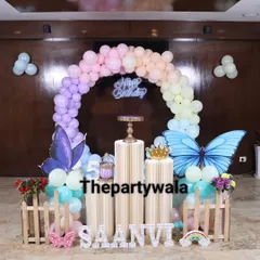 A beautiful butterfly theme with a pastel rainbow balloon arch and large butterfly wing cutouts. The light-up name sign and picket fence add a charming touch to this whimsical setup.