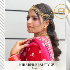 A side profile of a beautiful bride, highlighting the intricate matha patti and nose ring. The makeup is kept classic and clean to enhance her features without overpowering the traditional jewelry.