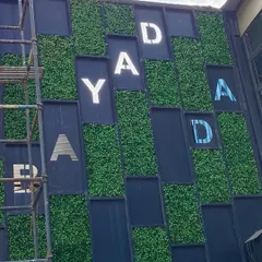 For the Bombay Adda facade, we created a unique design by setting artificial grass panels within a geometric grid, with the brand's letters integrated into the pattern for a striking architectural feature.