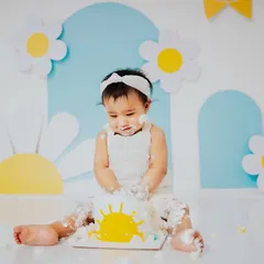 Getting right into the fun. This shot shows the beginning of the mess, as she curiously explores her sunshine cake during her first birthday photoshoot.