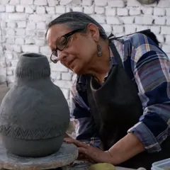A participant in a Raku workshop carefully carves patterns into her hand-built vessel. The studio provides a space for everyone to explore their own creative voice.