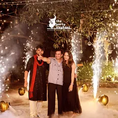 A perfect photo opportunity amidst the celebration. The guests are framed by dramatic cold pyro sparklers and a backdrop of low-lying fog, creating a truly memorable and cinematic shot.