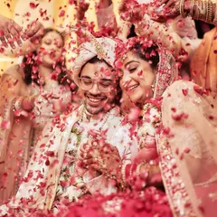 A shower of love. The couple is surrounded by family and friends, all showering them with petals in a moment of collective joy and blessing.