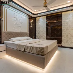 A master bedroom designed for ultimate comfort and elegance in Seawoods, Navi Mumbai. Notice the custom-designed headboard with intricate 3D relief work and gold accents, complemented by ambient lighting from the floating bed frame and designer pendant lights. The dark wood and light upholstery create a balanced, sophisticated retreat.