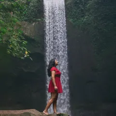 A powerful solo shot at Tibumana Waterfall. The contrast of the red dress against the lush greens and cascading water creates a striking, memorable portrait. I guide my clients to find poses that feel natural yet heroic.