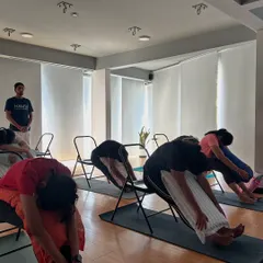 A supported forward bend over a chair, a key pose in our therapeutic sessions for releasing tension in the back and shoulders.