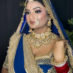 A side profile of the Rajputi bride, showcasing her elegant bun, traditional jewelry, and the flawless finish of her HD makeup against the studio backdrop.