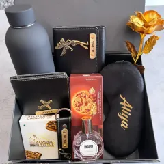 Here is the same all-black hamper packed neatly in a gift box. It features a personalized wallet, passport holder, bottle, keychain, and eye mask, along with some sweet treats and a golden rose.