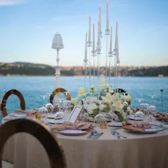 An elegant tablescape for a wedding reception by the sea, featuring tall candelabras and white floral arrangements that complement the beautiful water views.