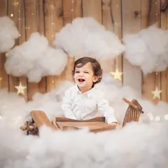Pure, unfiltered joy. This little pilot's laughter is everything. For his first birthday photoshoot, we created a magical sky with a wooden airplane and fluffy clouds, making his milestone celebration truly unforgettable.