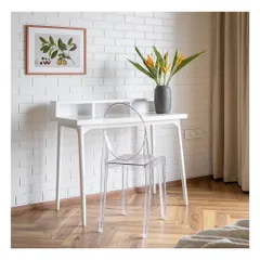 The study in 'Vishu Home' is a minimalist's dream. A clean white desk and a transparent ghost chair create a sense of lightness and space, set against a white brick-textured wall for a touch of industrial chic.