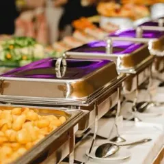 Food should be a feast for the eyes too. This is a snapshot of an elegant buffet arrangement, showcasing a variety of dishes in professional chafing dishes, ensuring the food stays warm and is presented beautifully for a large gathering.
