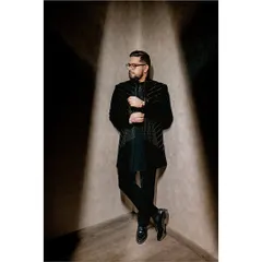 A dapper portrait of the groom, leaning against a corner with a spotlight creating a dramatic effect. This is a great example of a modern groom's portrait that is both stylish and strong.