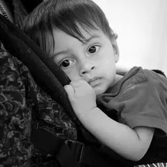 The warmth of a parent's embrace. This black and white photo of a baby in a carrier is interpretive, focusing on the feeling of safety and closeness.