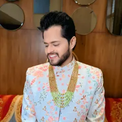 This groom's pastel floral sherwani is paired with a stunning multi-layered green bead necklace, adding a touch of modern royalty.