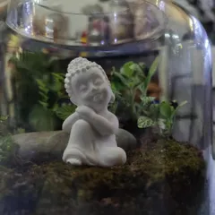 Personalize your terrarium to create a peaceful scene. This close-up shows a finished piece from one of our workshops, featuring a serene Buddha miniature nestled amongst fittonia plants and soft moss.