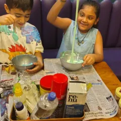 Getting messy is part of the fun! Two kids are completely absorbed in a slime-making workshop, mixing colors and ingredients to create their own gooey masterpieces.