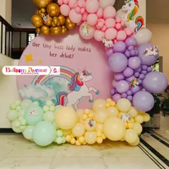 A close-up of the unicorn backdrop and the multi-colored balloon garland, featuring shades of pink, purple, yellow, and mint green.