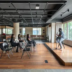 The central zone of our 'Chasing Tales' project was conceived as a versatile stage for community engagement. Here, it is configured for a live performance, demonstrating the space's capacity to transform from a co-working area into a vibrant venue for cultural events.
