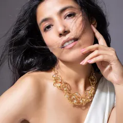 Another angle of the abstract gold necklace, this time with a soft, confident expression to highlight its elegance.