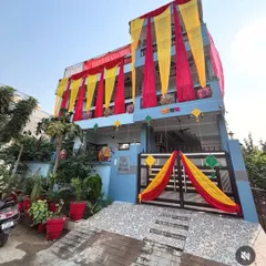 A daytime view of a house decorated with red and yellow drapes for a wedding. The entrance gate is also decorated to create a cohesive and festive look.